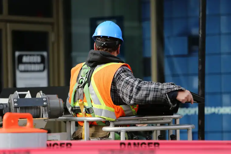 Worker in a hard hat and high-visibility vest operating a lift
