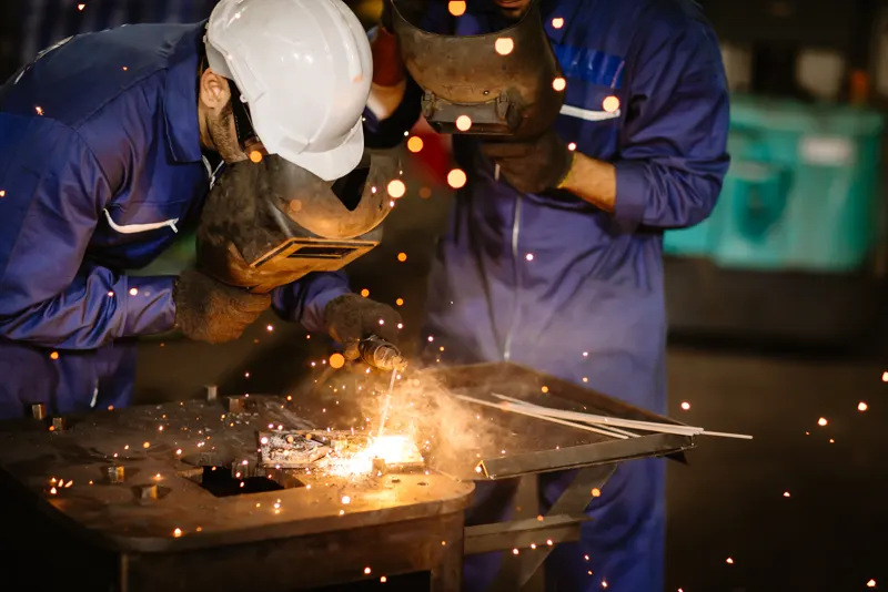 Welders working over sparks at a fabrication bench