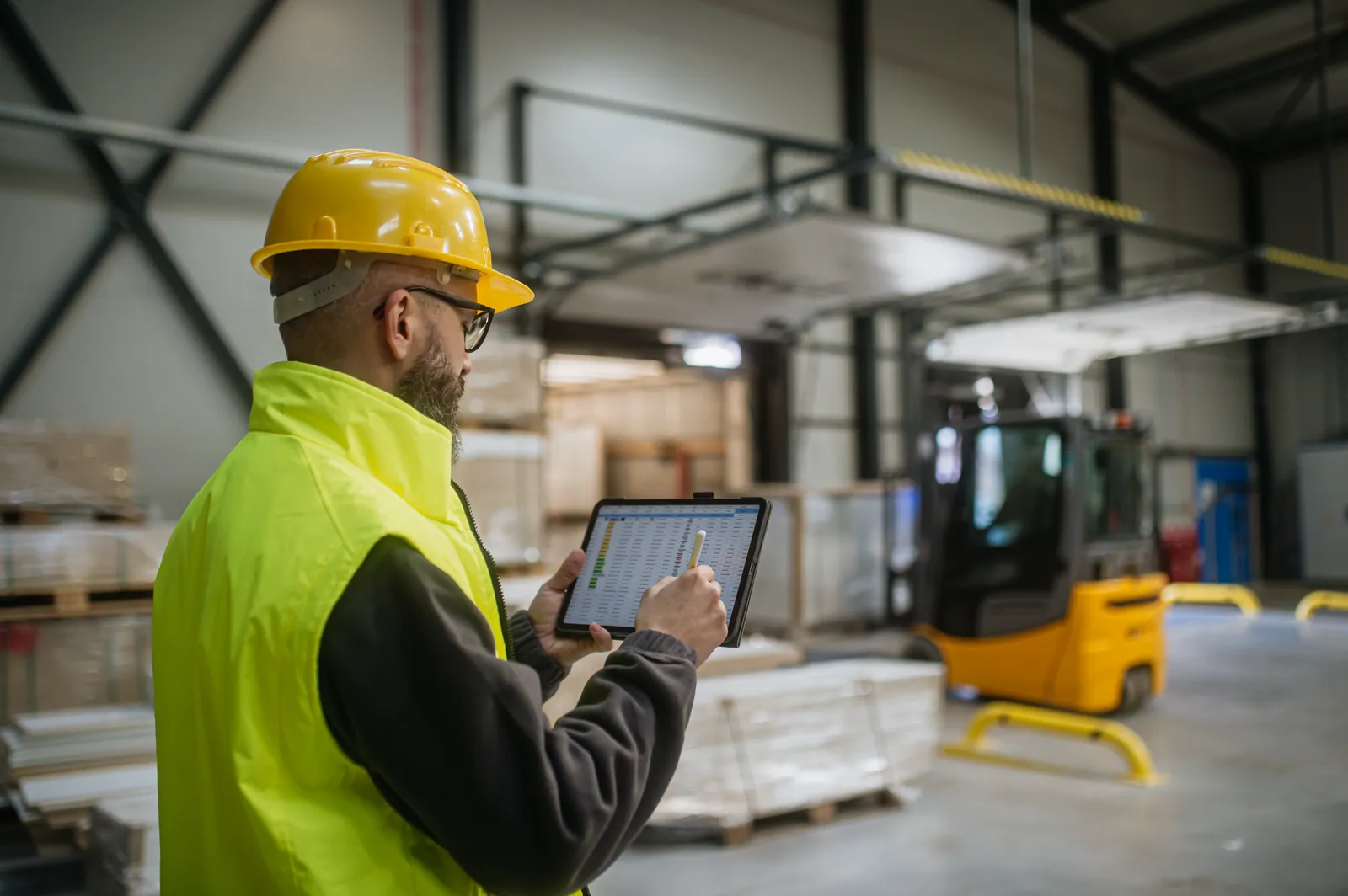 Safety inspector logging observations on a tablet in a warehouse