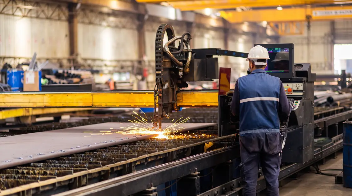Operator monitoring a CNC plasma cutting table on the plant floor