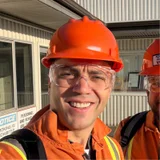 Sercan Esen wearing an orange hard hat and safety glasses at an industrial site