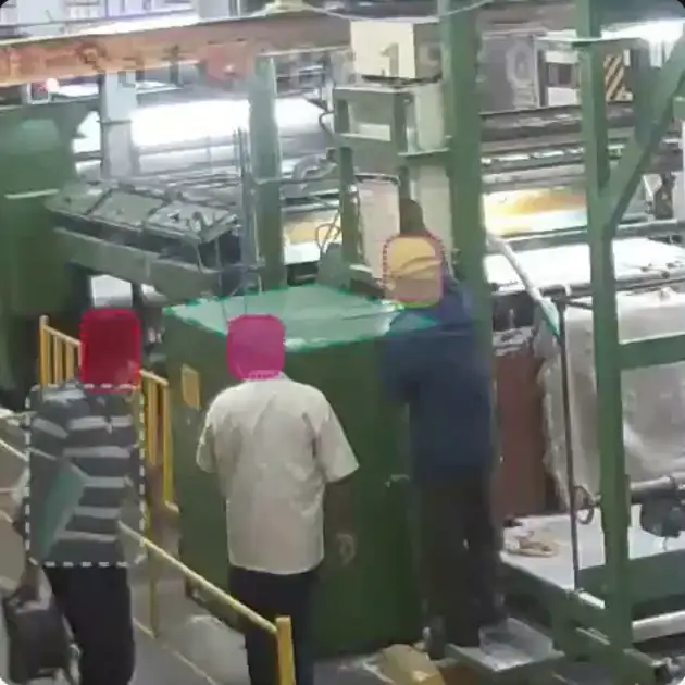 Anonymized workers at a production machine, one raised above the floor, with the machine top traced as a monitored zone