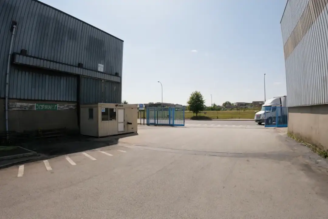 Facility perimeter with a gatehouse, blue fence gates, and a truck arriving at the yard entrance